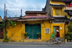 Vietnamese Women on Bike in Front of Yellow Building